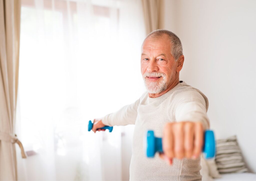 Elderly gentleman exercising at home with dumbbells.