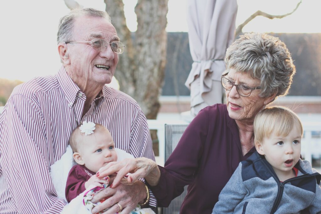 A senior couple holding their grand children.
