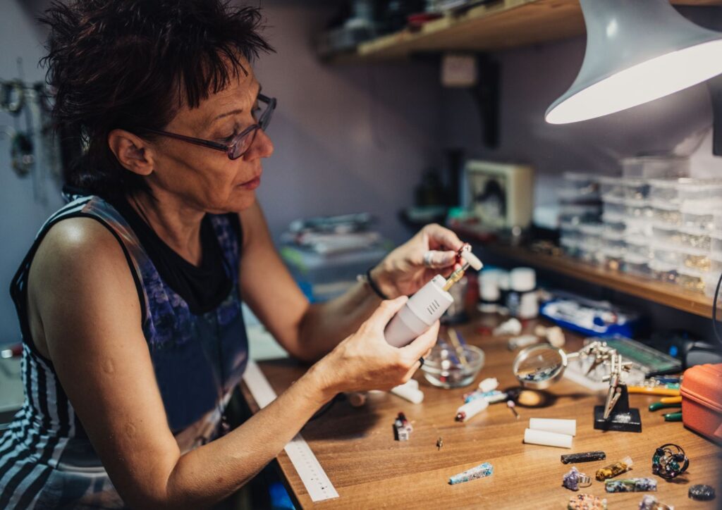 Mature woman crafting jewelry with meticulous skill and a lifetime of creative passion.