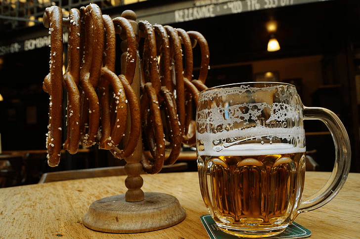An image of several pretzels on a rack with a mug of beer.