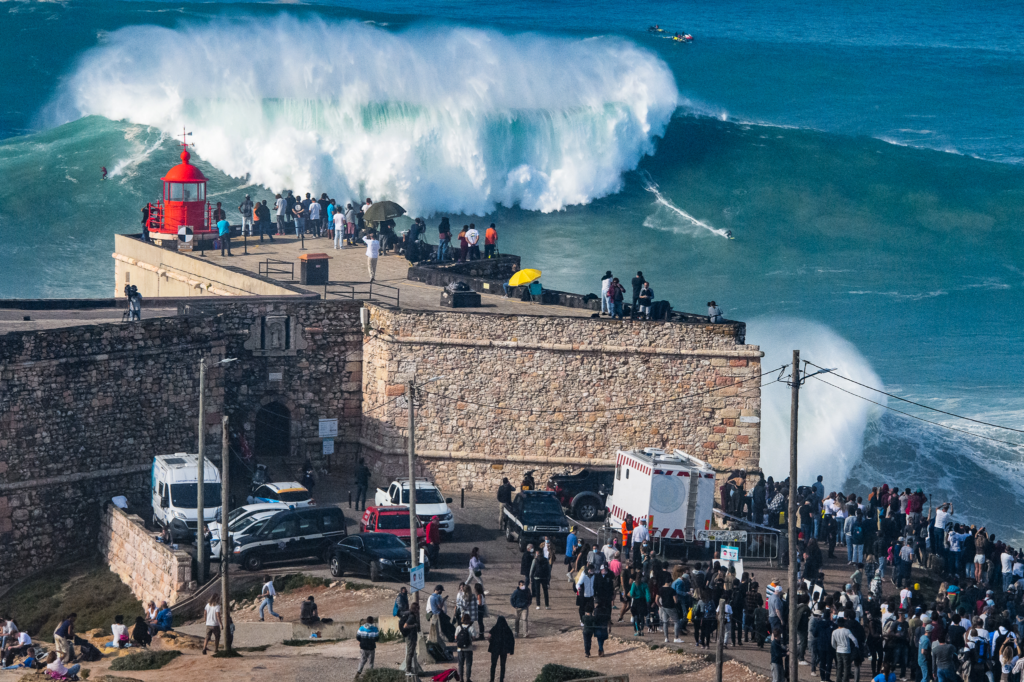 An image of tourists observing the large waves of Praia do Norte. 