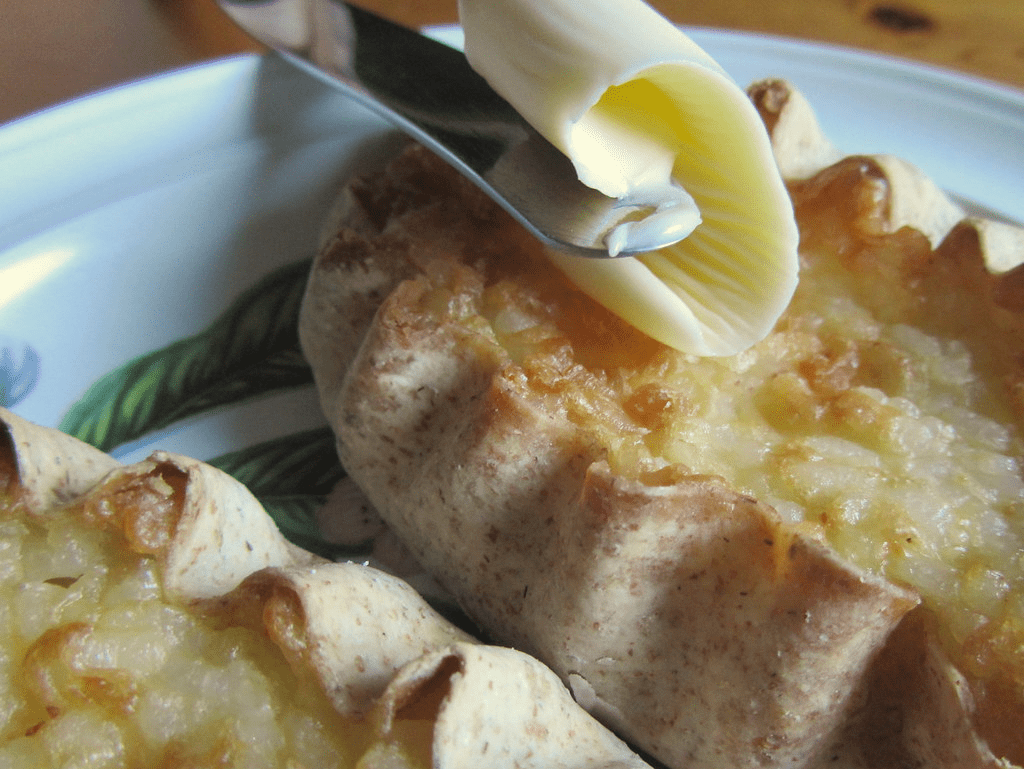 An image of two karjalanpiirakka served with butter. 