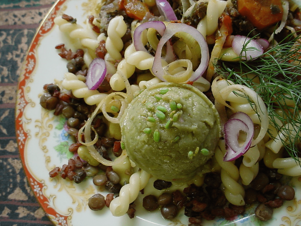 An image of a fava scoop on top of pasta and lentils.