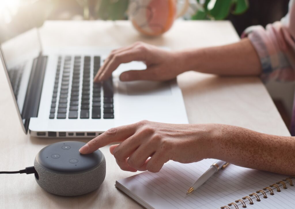 a person using a laptop and a smart speaker