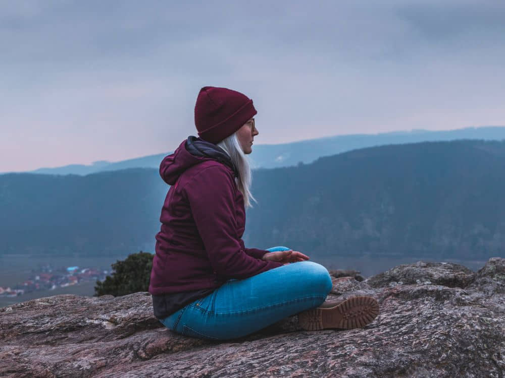 An image of a senior traveler sitting on a hill.