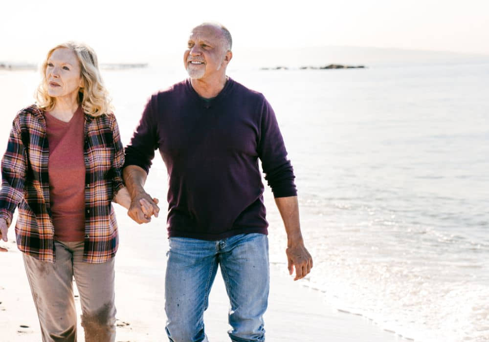 A retired couple walking on a beach