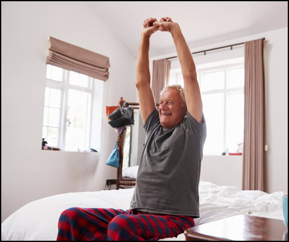 An image of a senior stretching in bed