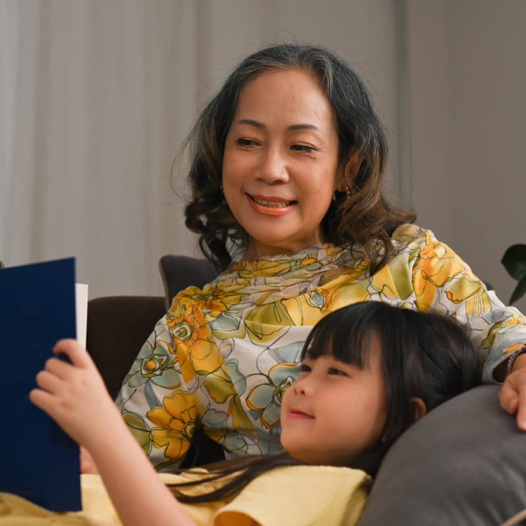 Loving grandmother telling story, reading fairy tale to little granddaughter.